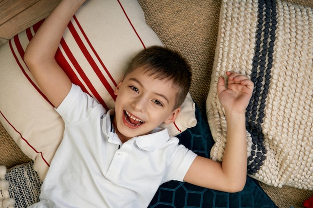 Beautiful boyl sdraiato sul pavimento e guarda la telecamera Il concetto di felicità amicizia dei bambini ragazzo sdraiato sul pavimento e sorridente