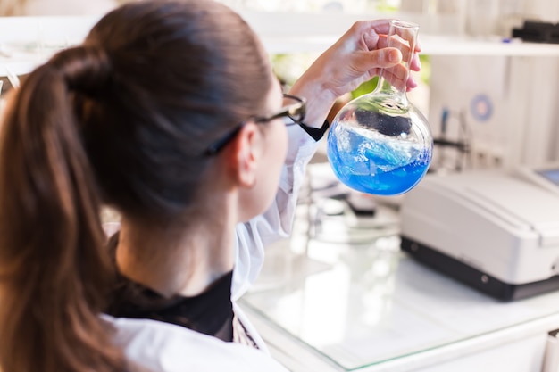 Becher con liquido nelle mani di donne scientifiche