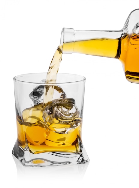 Becher di vetro con ghiaccio versa whisky dalla bottiglia