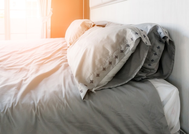 Bed-letto con cuscini e lenzuola bianche pulite nella stanza di bellezza