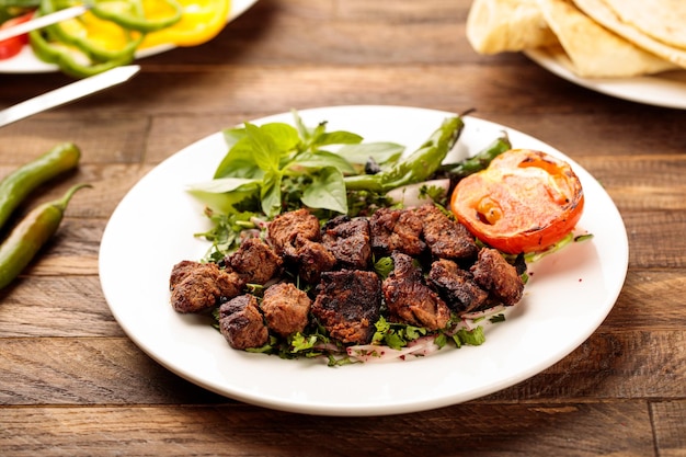 Beef Grill Tikka boti kabab con insalata di pomodoro e pane servito in un piatto isolato su un tavolo di legno