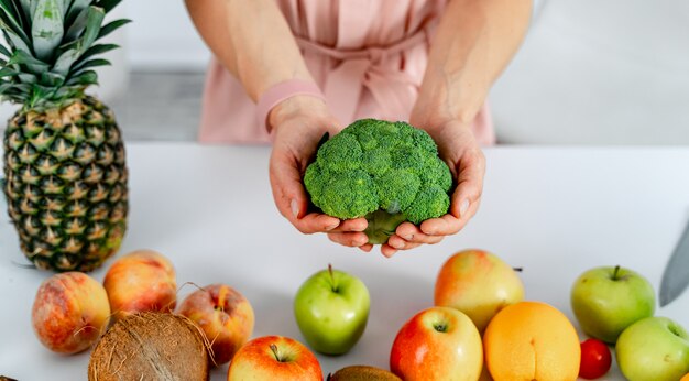 Bei broccoli freschi verdi in mani. Frutta e verdura su un tavolo.