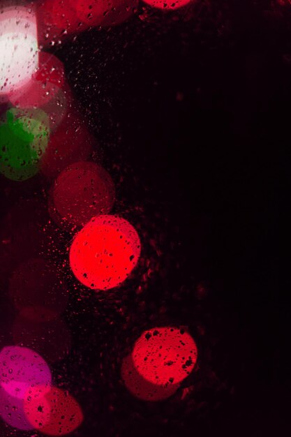 Bei cerchi rosa del bokeh con le gocce su fondo nero con lo spazio della copia