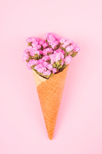 Bei fiori rosa in un cono di cialda per gelato su uno sfondo rosa brillante.