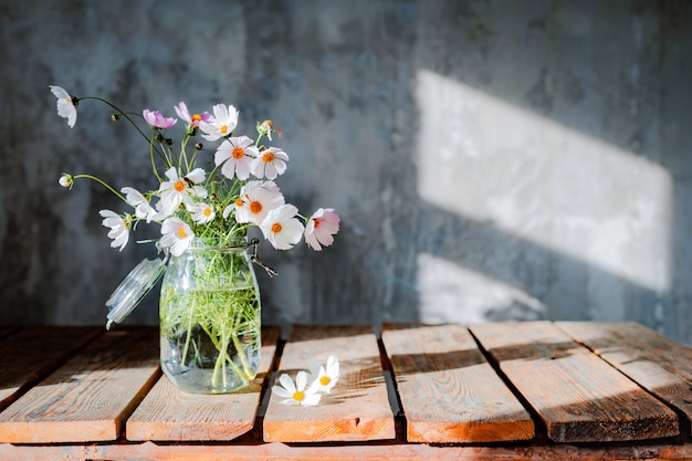 Bei mazzi di fiori di campo su un tavolo di legno su un muro di cemento freddo