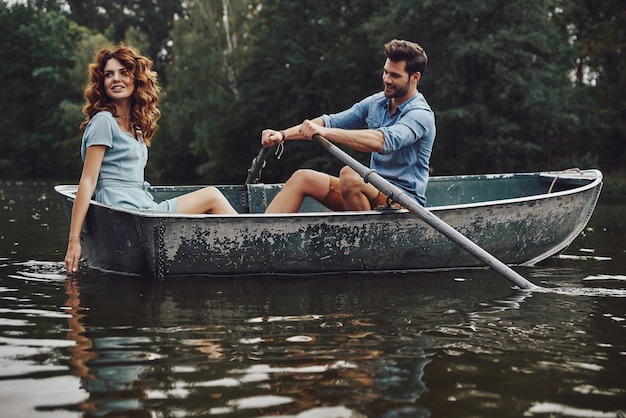 Bei tempi. Bella giovane coppia che si gode un appuntamento romantico mentre rema su una barca