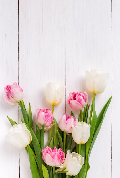 Bei tulipani su fondo di legno bianco