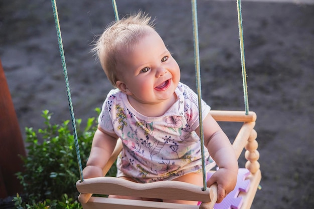 Bel bambino carino che oscilla nel cortile su un'altalena che si attacca