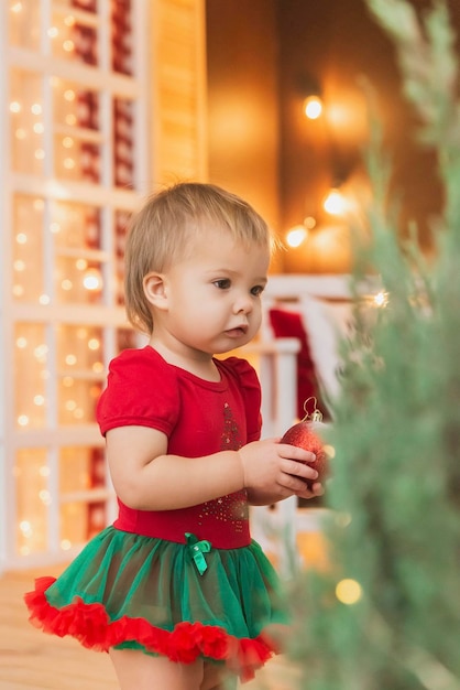 Bel bambino in costume di Capodanno in piedi vicino all'albero di Natale