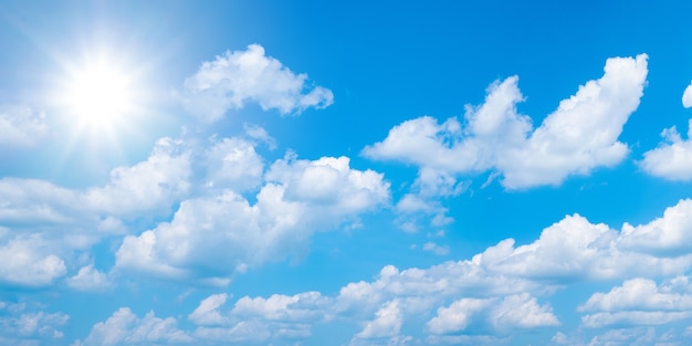 Bel cielo azzurro con nuvole bianche e sole, panarama di sfondo alla luce del sole