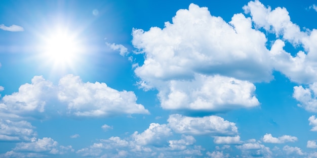 Bel cielo azzurro con nuvole bianche e sole, panarama di sfondo alla luce del sole