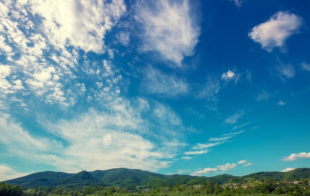 Bel cielo blu con soffici nuvole bianche sopra il crinale della montagna