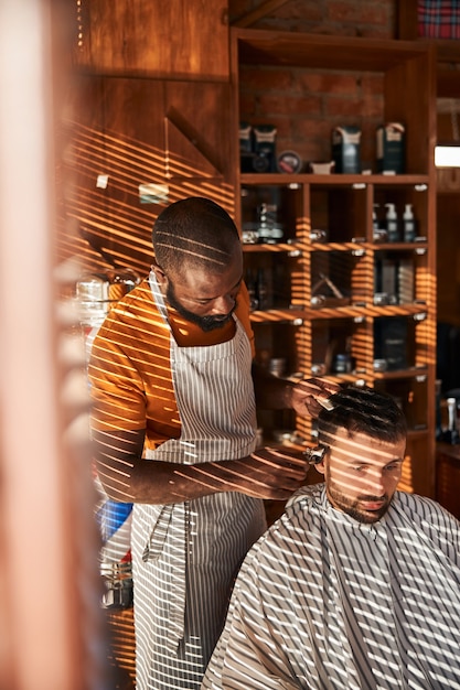 Bel cliente maschio che si fa tagliare i capelli dal barbiere