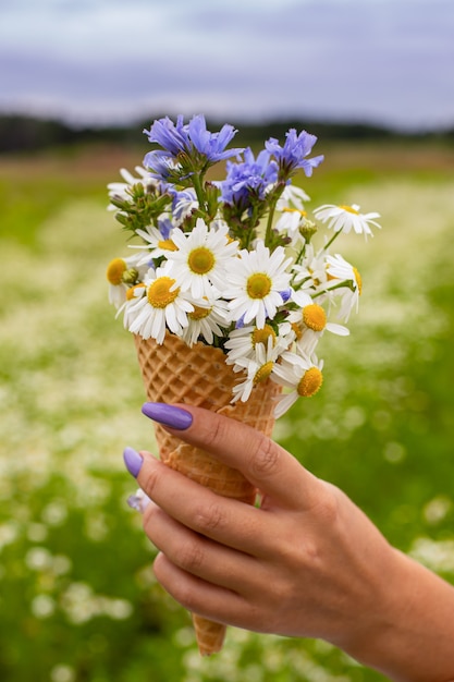 Bel fiore nel cono gelato in mano delle ragazze