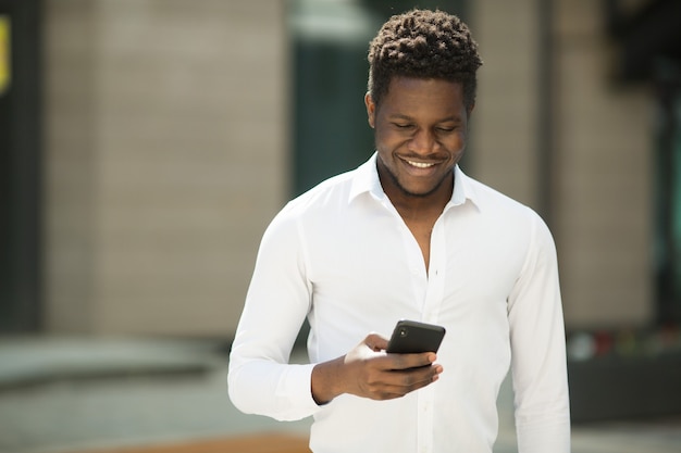 bel giovane africano in camicia con il telefono