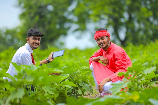 Bel giovane agronomo e agricoltore ispezionando il campo di melanzane con tablet
