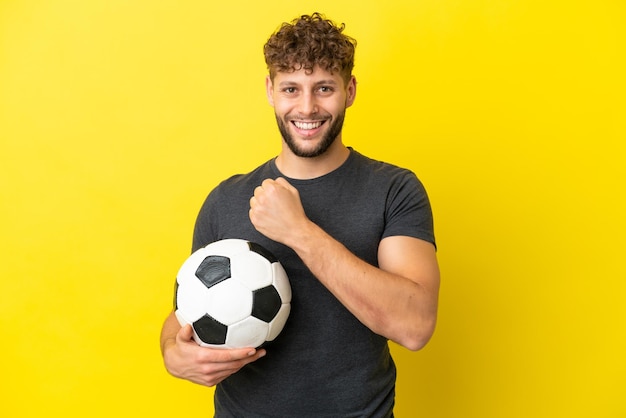 Bel giovane calciatore uomo isolato su sfondo giallo che celebra una vittoria