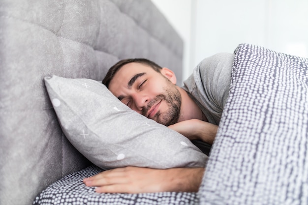 Bel giovane che dorme nella sua camera da letto