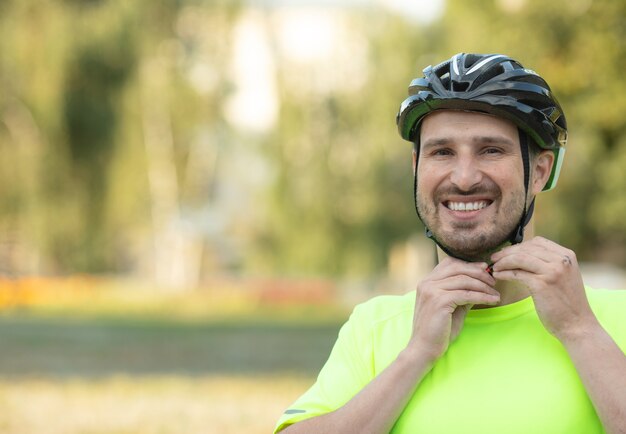 Bel giovane che indossa il casco da bicicletta nel parco