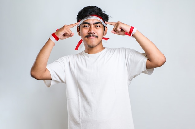 Bel giovane che indossa una camicia casual sorridente che punta alla testa con entrambe le mani dito, grande idea o pensiero, buona memoria su sfondo bianco