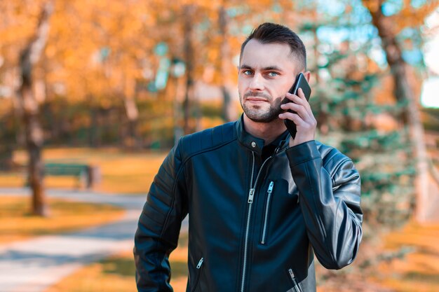 Bel giovane che parla al telefono nel bellissimo parco autunnale