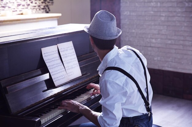 Bel giovane con cappello che fa musica per pianoforte