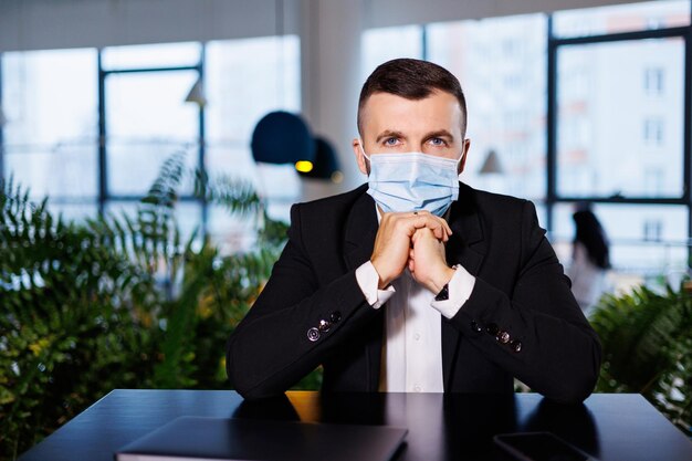 Bel giovane con una maschera che lavora in un bar con un laptop durante la pandemia di coronavirus