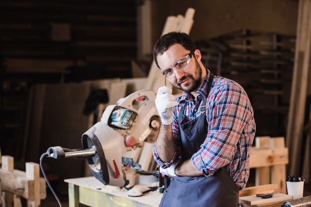 Bel giovane falegname tuttofare in officina, sorridente