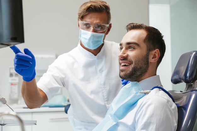 bel giovane felice seduto nel centro medico dentista guardando la scansione a raggi x