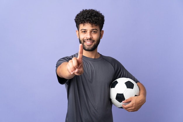 Bel giovane giocatore di football marocchino uomo isolato su sfondo viola che mostra e solleva un dito