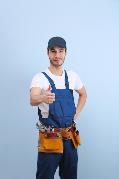 Bel giovane idraulico in uniforme su sfondo colorato