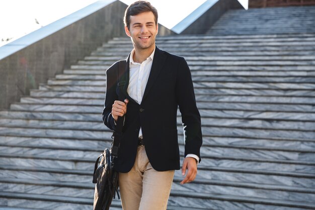 Bel giovane imprenditore borsa per il trasporto, passeggiate all'aperto