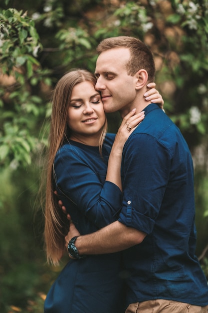 Bel giovane ragazzo con una ragazza in piedi nel giardino di primavera. Le coppie romantiche stanno camminando nel parco. Concetto di relazione felice