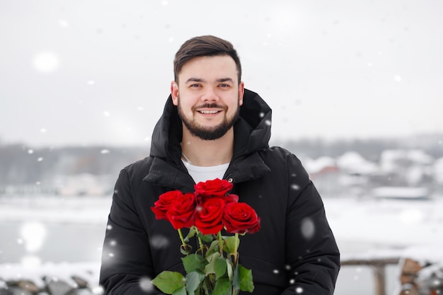 Bel giovane romantico con bouquet di rose rosse in mano