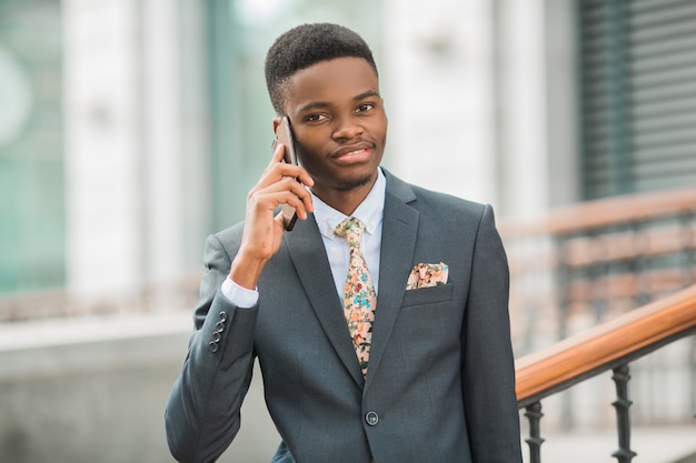 bel giovane uomo africano in un vestito parlando al telefono