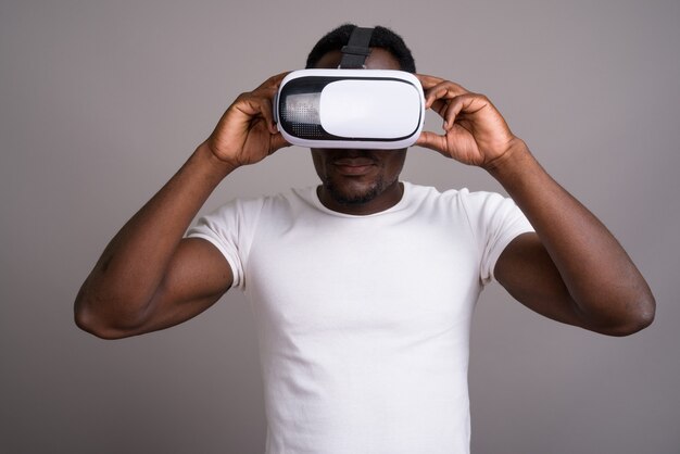 Bel giovane uomo africano utilizzando cuffie da realtà virtuale contro