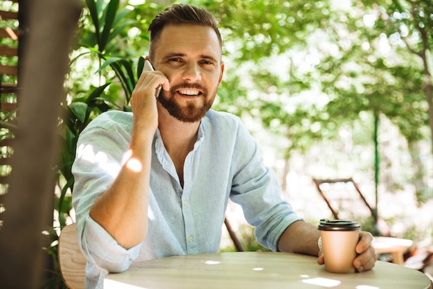 Bel giovane uomo barbuto felice che parla dal telefono cellulare.