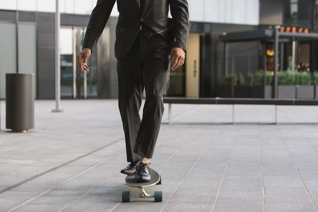 Bel giovane uomo d'affari con il suo longboard moderno