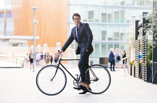 Bel giovane uomo d'affari con la sua bicicletta moderna.