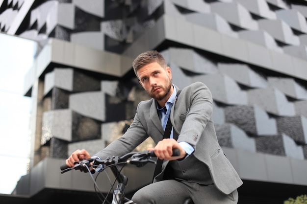 Bel giovane uomo d'affari in bicicletta all'aperto in città.