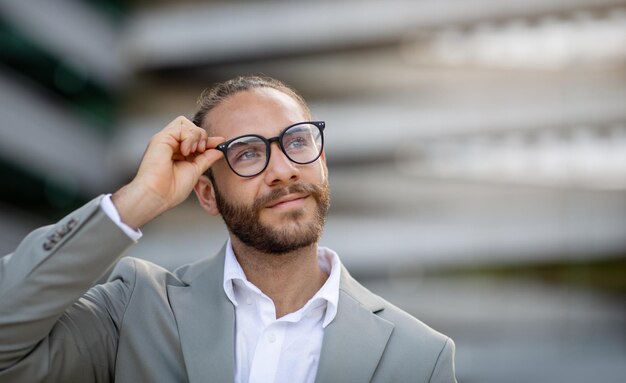 Bel giovane uomo d'affari in occhiali alla moda in piedi all'aperto sulla strada della città