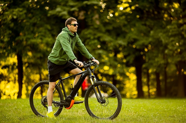 Bel giovane uomo equitazione ebike nel parco