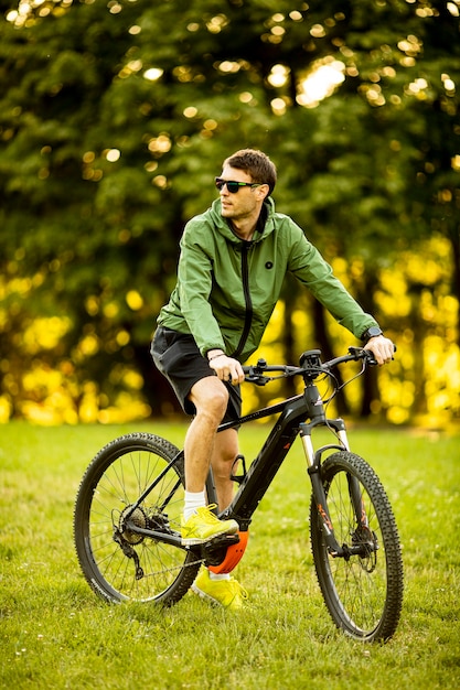 Bel giovane uomo equitazione ebike nel parco