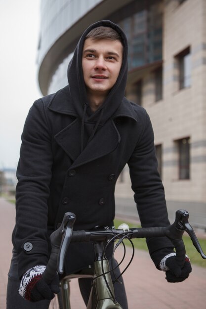 Bel giovane uomo in bicicletta in città