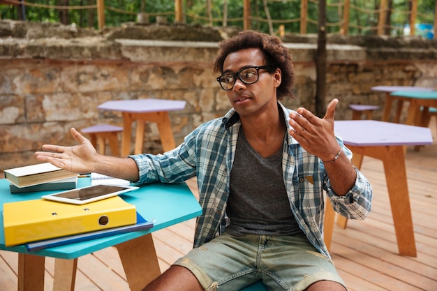 Bel giovane uomo seduto e parlando in un caffè all'aperto