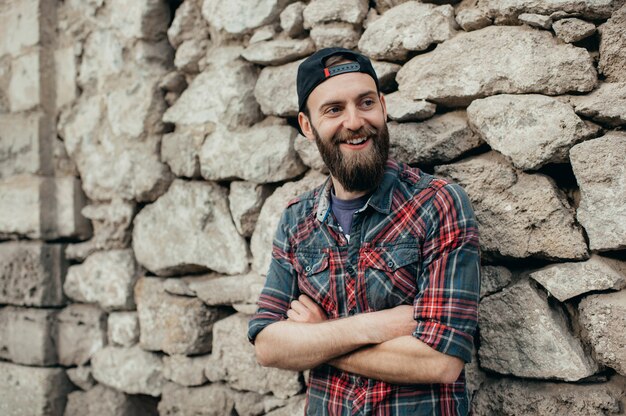 Bel giovane uomo sorridente con la barba sorridente su sfondo di pietra