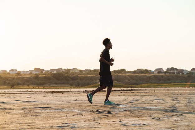 Bel giovane uomo sportivo forte che corre all'aperto