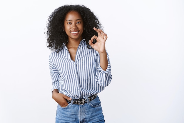 Bel lavoro, risultato fantastico. Soddisfatto compiaciuto attraente sorridente donna afroamericana che mostra bene ok gesto ghignando felice servizio eccellente raccomandando, parere positivo affermativo