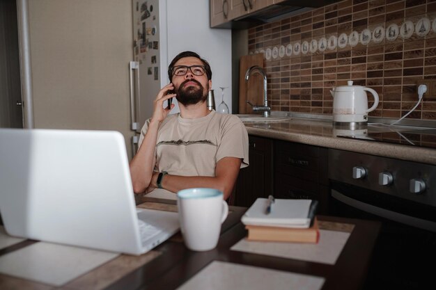 Bel libero professionista sorridente che lavora a distanza da casa Sta parlando al telefono