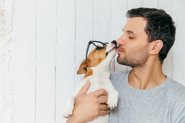 Bel maschio sta lateralmente, bacia il suo cane jack russell terrier, ha una buona relazione